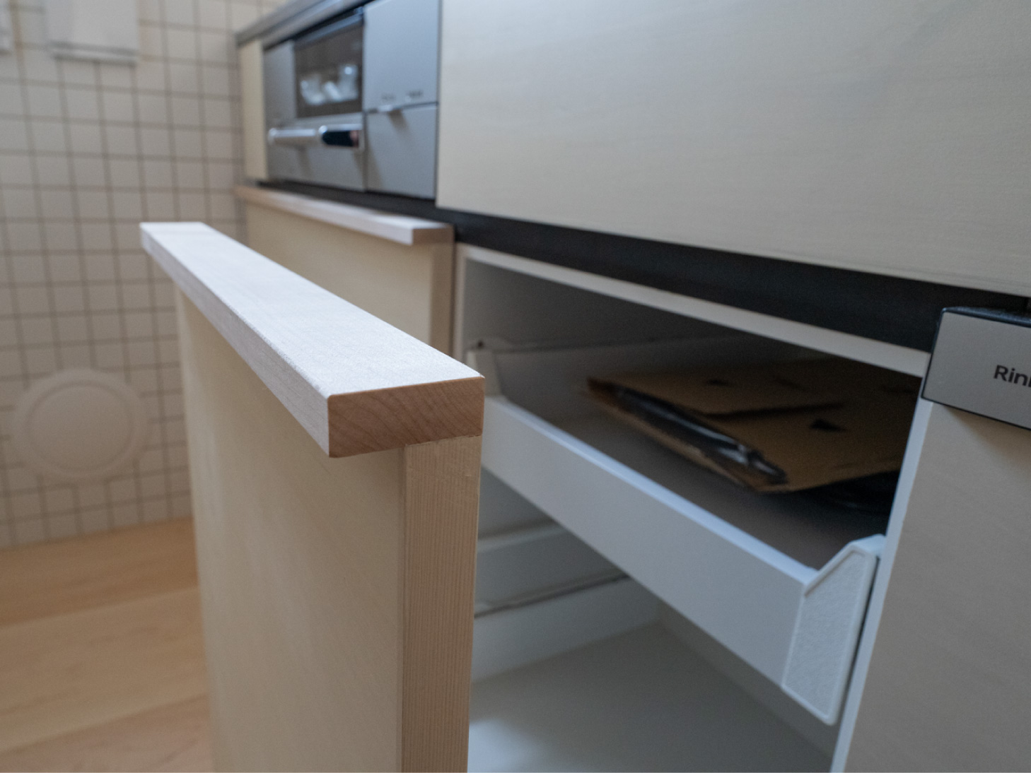シナ合板で作った扉には、下の部分をくりぬいた無垢材の取っ手