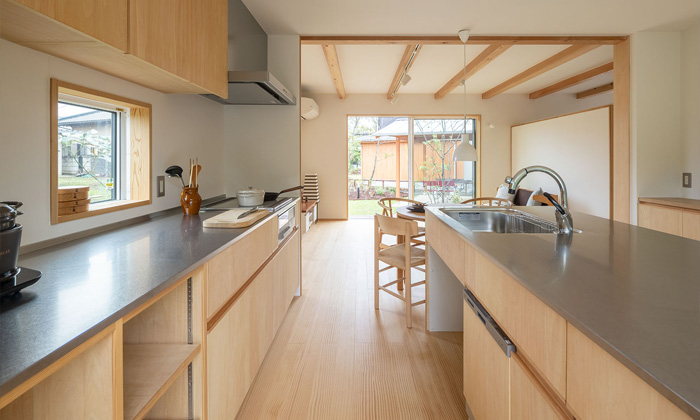 出っ張りのない取っ手と材質で柔らかさを感じるオープン造作キッチン実例